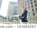 A blonde businesswoman with her arms crossed in the business district. 141669267