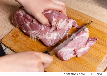 Slicing pork meat into equal steak portions stock photo 141669505