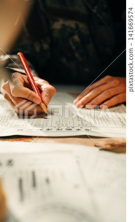 Person writing over archival military papers 141669574
