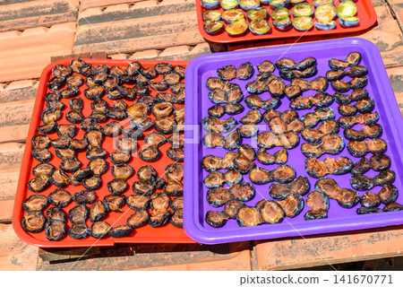 Sun drying plum fruit slices on colorful trays Sun drying plum fruit slices on colorful trays 141670771