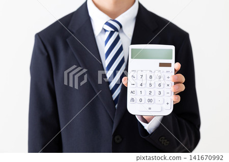 A young businessman in a business suit holding a white calculator. A young businessman in a business suit holding a white calculator. 141670992