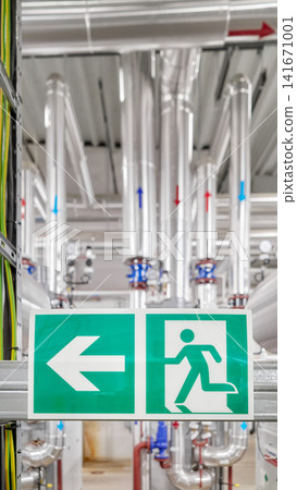Industrial emergency exit sign with a directional arrow inside a district heating plant, selective focus. Industrial emergency exit sign with a directional arrow inside a district heating plant, selective focus. 141671001