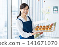 A middle-aged woman selling bread at a cafe. Photo courtesy of Denpa Gakuen Educational Foundation, Tokyo Electronics College. 141671070