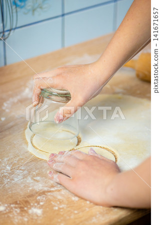 Stamping out circles from dough sheet with glass photo Stamping out circles from dough sheet with glass photo 141671657