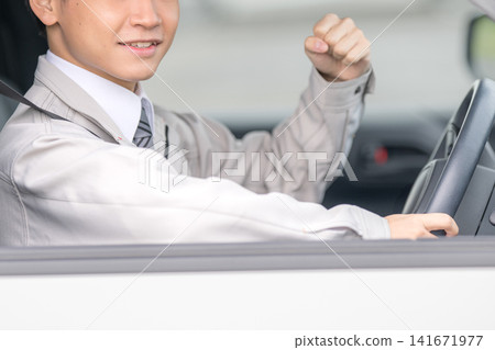 一名男子在駕車時做出勝利的手勢;一幅展現駕車和喜悅的畫面。 一名男子在駕車時做出勝利的手勢;一幅展現駕車和喜悅的畫面。 141671977