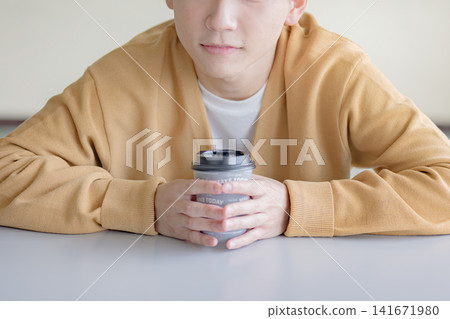 一名男子手持咖啡杯,展現出放鬆片刻的畫面。 一名男子手持咖啡杯,展現出放鬆片刻的畫面。 141671980
