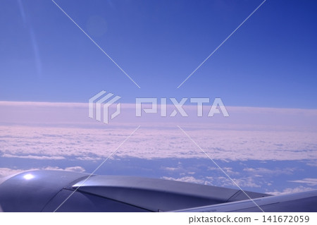 A sea of clouds stretching across the blue sky, with the wing of an airplane in the background. A sea of clouds stretching across the blue sky, with the wing of an airplane in the background. 141672059