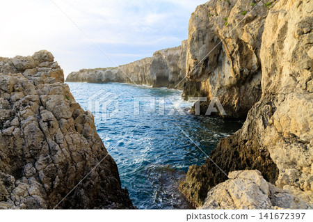 Dramatic rock formations create a natural grotto along a wild coastline bathed in warm sunshine Dramatic rock formations create a natural grotto along a wild coastline bathed in warm sunshine 141672397