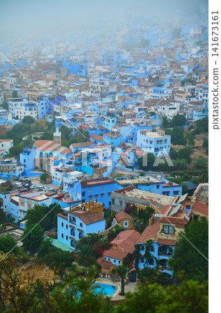 Aerial view of Chefchaouen blue city with densely packed houses and misty hills Aerial view of Chefchaouen blue city with densely packed houses and misty hills 141673161