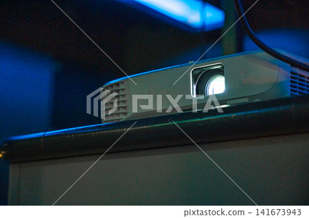 A projector lights up in an office room, an image of technology. A projector lights up in an office room, an image of technology. 141673943