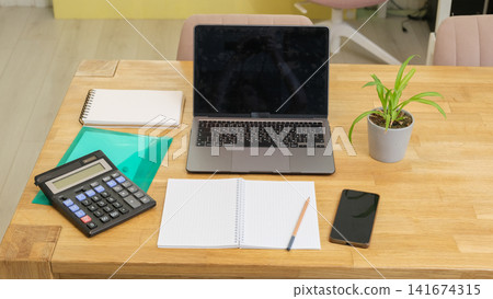 Modern home office workspace setup for freelance or study. Laptop, calculator, notebook, document folder. Remote Accounting, Home Bookkeeping. Wooden desk layout. Financial Planning. Work Life Balance Modern home office workspace setup for freelance or study. Laptop, calculator, notebook, document folder. Remote Accounting, Home Bookkeeping. Wooden desk layout. Financial Planning. Work Life Balance 141674315