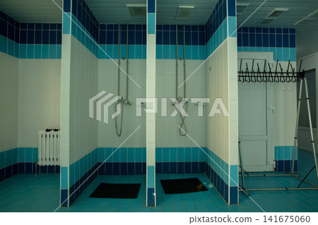 Shower area in changing room of a sports facility with clean tiles and simple design Shower area in changing room of a sports facility with clean tiles and simple design 141675060