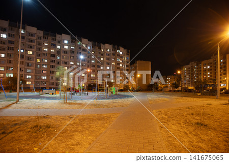 Playground in a residential area illuminated at night with lights and buildings in the background Playground in a residential area illuminated at night with lights and buildings in the background 141675065