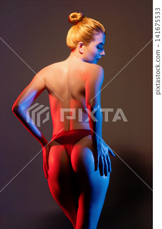 Female figure in red underwear under dramatic red and blue studio lighting Female figure in red underwear under dramatic red and blue studio lighting 141675533