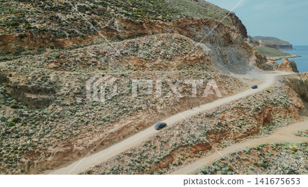 High angle aerial view of cars driving along winding dirt road on mountain slope to Balos lagoon in Gramvousa Crete Greece for travel adventure stock photo High angle aerial view of cars driving along winding dirt road on mountain slope to Balos lagoon in Gramvousa Crete Greece for travel adventure stock photo 141675653