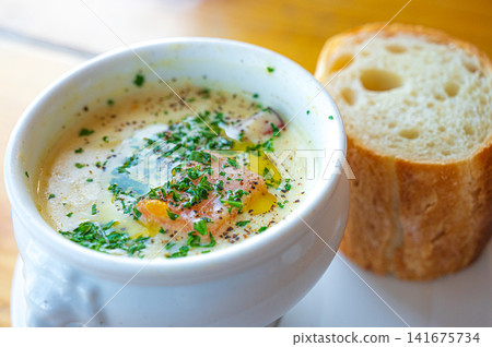 A cream soup in a white cup and bread – an image of lunch. A cream soup in a white cup and bread – an image of lunch. 141675734