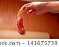 一隻手拿著蟹腿的特寫鏡頭，以及一道螃蟹菜餚的圖片。 141675739