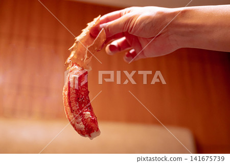 A close-up of a crab leg held in a hand, an image of a crab dish. A close-up of a crab leg held in a hand, an image of a crab dish. 141675739