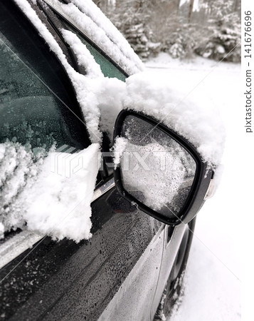 Car side mirror and window covered in a thick layer of snow and ice after a snowfall. Car side mirror and window covered in a thick layer of snow and ice after a snowfall. 141676696