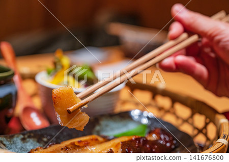 The moment you pick up the dengaku (grilled tofu with miso paste) from the bamboo basket with chopsticks, served on a Japanese meal tray. The moment you pick up the dengaku (grilled tofu with miso paste) from the bamboo basket with chopsticks, served on a Japanese meal tray. 141676800