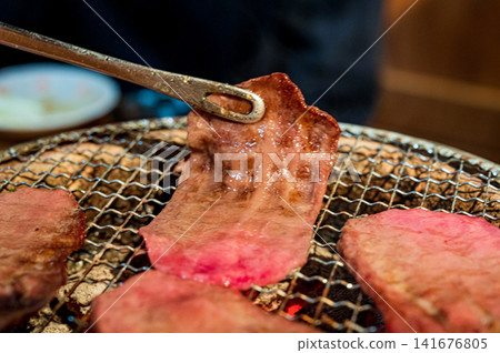 The moment you lift the yakiniku from the grill, you grab the wagyu beef with tongs. The moment you lift the yakiniku from the grill, you grab the wagyu beef with tongs. 141676805