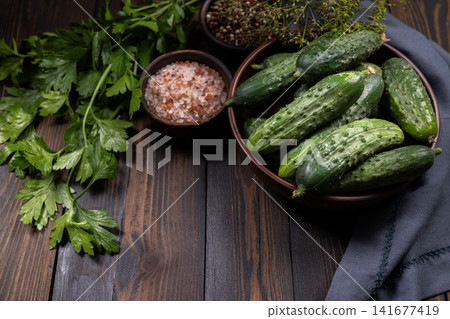 Fresh cucumbers, herbs, and spices on wooden table 141677419