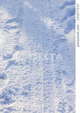 Snow covered path with tire tracks in winter Snow covered path with tire tracks in winter 141677537