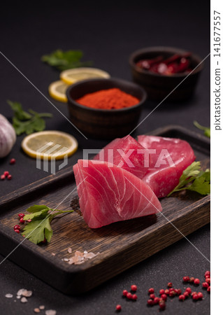 Raw tuna steaks preparing with spices and lemon slices Raw tuna steaks preparing with spices and lemon slices 141677557