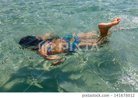 Child Swimming Underwater in Crystal Clear Sea During Summer Vacation 141678012