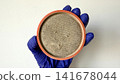 Dirty Round Air Filter Held in Gloved Hand for Maintenance and Replacement 141678044
