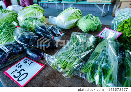 一個直接販售新鮮採摘蔬菜的攤位,茄子和高麗菜上都貼著手寫的價格標籤。 一個直接販售新鮮採摘蔬菜的攤位,茄子和高麗菜上都貼著手寫的價格標籤。 141678577