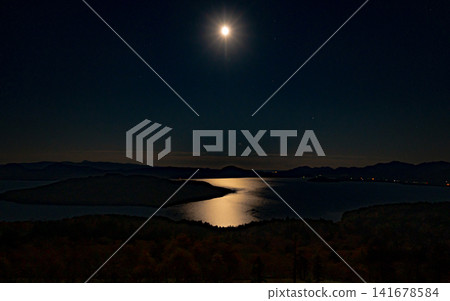 The moonlight illuminates the lakeshore at night, creating a magical shimmer on the water's surface. The moonlight illuminates the lakeshore at night, creating a magical shimmer on the water's surface. 141678584
