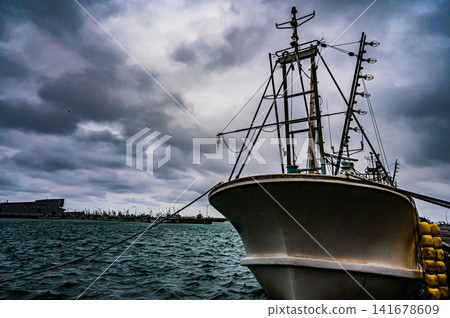 漁船停泊在港口,陰天下的港口小鎮景象。 漁船停泊在港口,陰天下的港口小鎮景象。 141678609