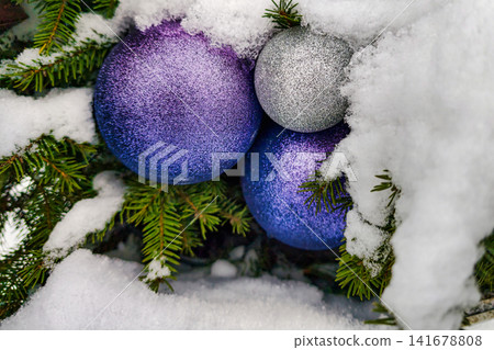 Christmas tree stands adorned with purple and silver ornaments surrounded by fresh snow in a winter landscape Christmas tree stands adorned with purple and silver ornaments surrounded by fresh snow in a winter landscape 141678808