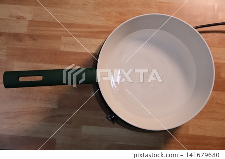 Frying Pan with Green Handle on Wooden Countertop Frying Pan with Green Handle on Wooden Countertop 141679680