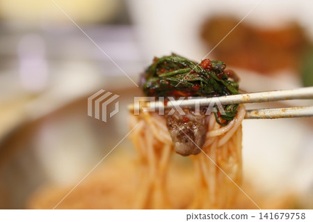 Chopsticks Holding Spicy Noodles with Leafy Greens Chopsticks Holding Spicy Noodles with Leafy Greens 141679758