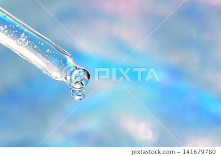 Close-up pipette with a clear water drop against a soft blue bokeh background, macro beauty shot Close-up pipette with a clear water drop against a soft blue bokeh background, macro beauty shot 141679780