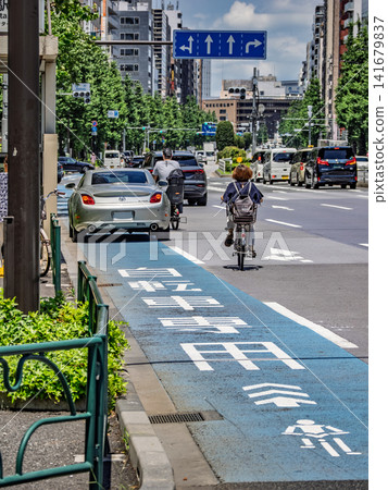 Two cyclists change course onto the road to avoid an illegally parked vehicle (vertical composition). Two cyclists change course onto the road to avoid an illegally parked vehicle (vertical composition). 141679837