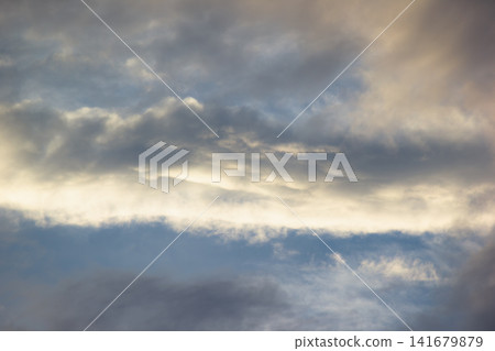 Dramatic dark storm clouds catching golden warm sunlight during sunset Dramatic dark storm clouds catching golden warm sunlight during sunset 141679879