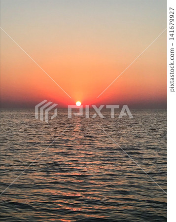 Minimal sunrise seascape with the sun on the horizon, pastel gradient sky and small rolling waves on a quiet beach. Clean copy space works for web banners, wellness and travel concepts, meditation bac Minimal sunrise seascape with the sun on the horizon, pastel gradient sky and small rolling waves on a quiet beach. Clean copy space works for web banners, wellness and travel concepts, meditation bac 141679927