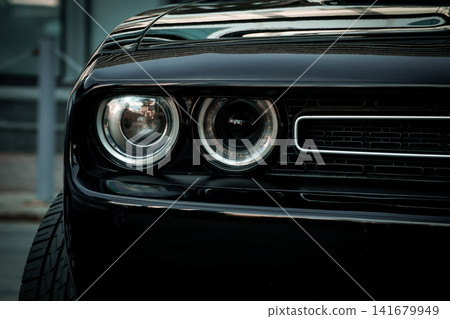 Black Muscle Car Front End Close Up with Dual Headlights and Aggressive Grille Black Muscle Car Front End Close Up with Dual Headlights and Aggressive Grille 141679949