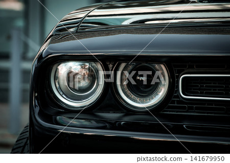 Black Muscle Car Front End Close Up with Dual Headlights and Aggressive Grille Black Muscle Car Front End Close Up with Dual Headlights and Aggressive Grille 141679950