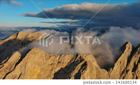 Amazing rocky mountains in clouds at sunset Amazing rocky mountains in clouds at sunset 141680134