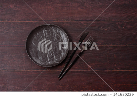An empty round ceramic plate on a dark, textured brown background. An empty round plate An empty round ceramic plate on a dark, textured brown background. An empty round plate 141680229