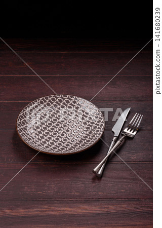 An empty round ceramic plate on a dark, textured brown background. An empty round plate An empty round ceramic plate on a dark, textured brown background. An empty round plate 141680239
