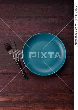 An empty round ceramic plate on a dark, textured brown background. An empty round plate An empty round ceramic plate on a dark, textured brown background. An empty round plate 141680275