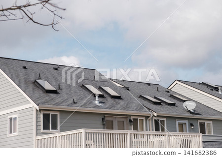 A close-up of grey townhouse roofs featuring multiple skylights, a satellite dish, and white railings. - March, 09 2026, Milton WA, USA A close-up of grey townhouse roofs featuring multiple skylights, a satellite dish, and white railings. - March, 09 2026, Milton WA, USA 141682386