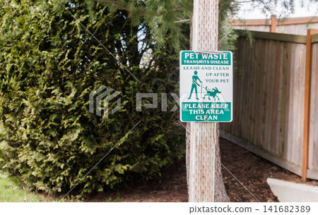 A green pet waste warning sign mounted on a wooden post next to a fence - March, 09 2026, Milton WA, USA A green pet waste warning sign mounted on a wooden post next to a fence - March, 09 2026, Milton WA, USA 141682389