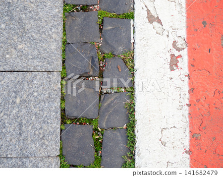 Border between running track and street paving stones. Treadmill concept. Surface for cycling. Infrastructure of a modern city. Border between running track and street paving stones. Treadmill concept. Surface for cycling. Infrastructure of a modern city. 141682479