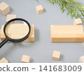 Business materials featuring a magnifying glass and wooden blocks, evoking images of research and analysis. 141683009